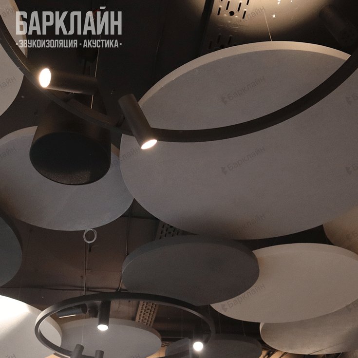 Дизайнерский потолок с круглыми акустическими островами и светильниками в кинозале.